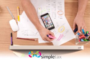 Person writing with paper, phone, imac